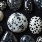 A side-by-side comparison of Snowflake Obsidian, a black stone with grey patterns, and Dalmatian Jasper, a white stone with black spots.