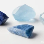 A lineup of the best blue crystals for the throat chakra, including Lapis Lazuli, Aquamarine, and Blue Lace Agate, on a white background.